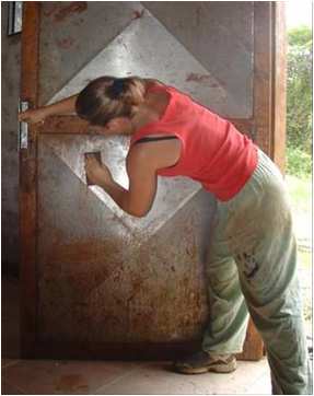 Corrie Sample sanding rusty door at IRR compound in Venezuela