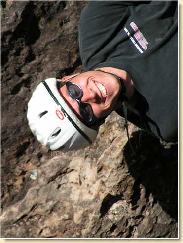 Smiling Daniel Adams rappelling upside down